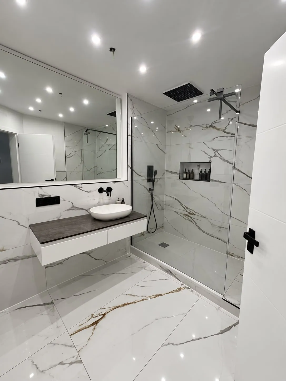 Bad mit weißen Großformatfliesen in Marmoroptik an Wand und Boden, Walk-in-Dusche mit Regendusche und Wandnische, schwebender Waschtisch